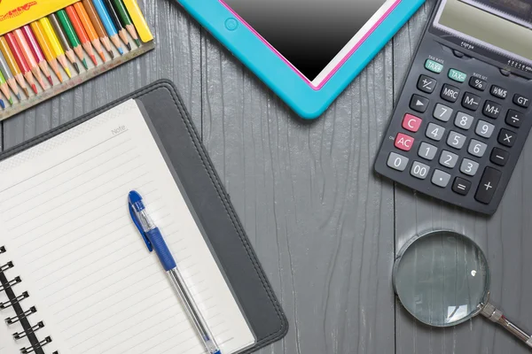 Defter, kalem, renkli kalem, Büyüteç'i hesap makinesi ve tablet PC'de ahşap arka plan masa. İş kavramı