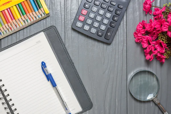 Defter, kalem, renkli kalem, ahşap masa arka plan üzerinde Büyüteç'i, hesap makinesi ve tablet pc. İş kavramı
