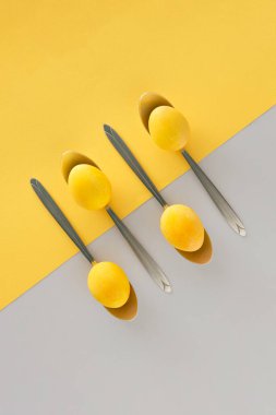 2021 Paskalya yumurtası masada kaşıkla servis ediliyor. Düz sarı ve gri arka plan yatıyordu. Sağlıklı gıda şenlik düzenlemesi.