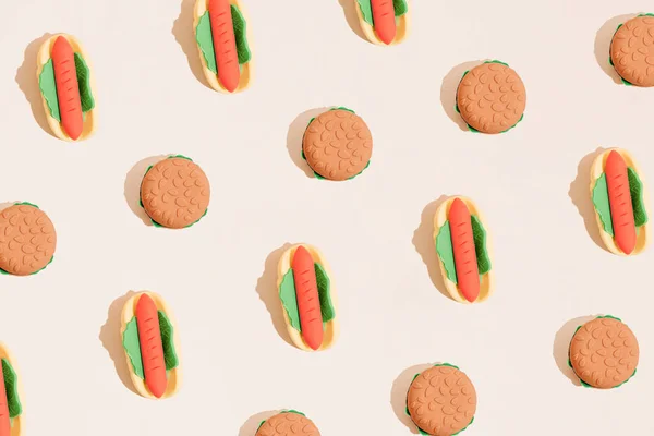 Hot dog and hamburger fast food pattern on pastel beige background. Minimal junk food flat lay concept.