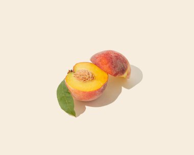 Asgari yaz meyve aranjmanı, güneş ışığı, sulu, olgun, turuncu-sarı, yeşil yapraklı şeftali, pastel bej arka planda izole edilmiş. Güneş ve gölge. Organik, çiğ, doğal sağlıklı gıda konsepti.