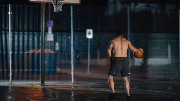 Спортивний юний баскетболіст - баскетболіст грає в баскетбол і кидає м "яч у сірому положенні в житловому сусідстві з вуличним майданчиком. — стокове фото