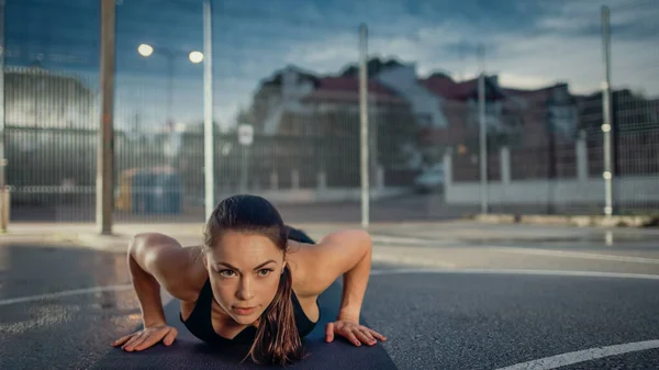 Beautiful Energetic Fitness Girl Doing Push Up Exercises. She is Doing a Workout in a Fenced Outdoor Basketball Court. Evening After Rain in a Residential Neighborhood Area. — Stock Photo, Image