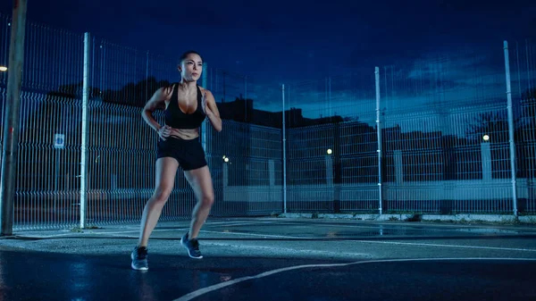 Vacker Energetic Fitness Girl gör fotarbete löpning borr. Hon gör ett träningspass i en inhägnad utomhus basket domstol. Natt efter regn i ett bostadsområde. — Stockfoto