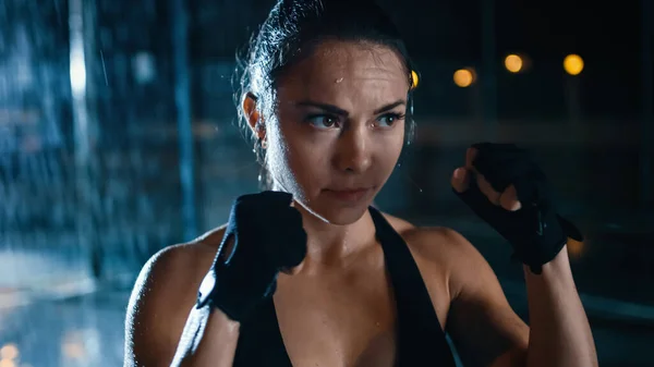 Beautiful Sporty Fitness Girl is Doing Sharowboxing Exercises. She is Doing a Workout at Night in Heavy Rain with One Light Behind Her. — Stock Photo, Image