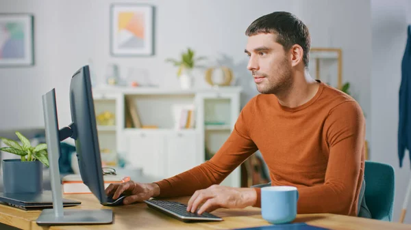 Ritratto di bel giovane che lavora su un personal computer da casa. In accogliente luminoso soggiorno Man Naviga attraverso Internet. — Foto Stock