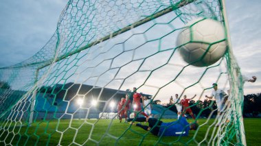 Futbol Şampiyonası 'nda kaleci golleri savunmaya çalışır ama topu yakalayamaz. İçinde top olan internetten çekilmiş bir fotoğraf. Tüm Stadyum Görünür.