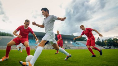 Profesyonel Futbolcu Topla Öncülük Ediyor, Rakiplerinin Kayan Aletleri Ustaca Sürüyor ve Baypas Ediyor. İki Profesyonel Futbol Takımı Oynuyor. Düşük Açı Vuruşu.