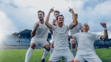 Futbol takımının kaptanı dizlerinin üzerine çöküp muhteşem zaferi kutluyor ve EVET jest şampiyonu oluyor. Başarılı Mutlu Futbolcular Zaferi Kutluyor.