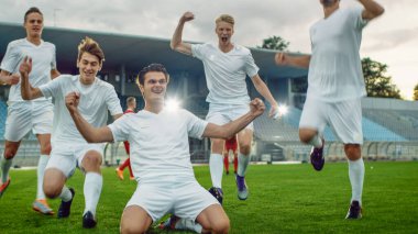 Futbol takımının kaptanı dizlerinin üzerine çöküp muhteşem zaferi kutluyor ve EVET jest şampiyonu oluyor. Başarılı Mutlu Futbolcular Zaferi Kutluyor.