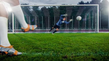 Anonim Futbolcu Penaltı Topunu Tekmeliyor, Profesyonel Kaleci Kalede Duruyor, Topu Yakalamak İçin Sıçrıyor.