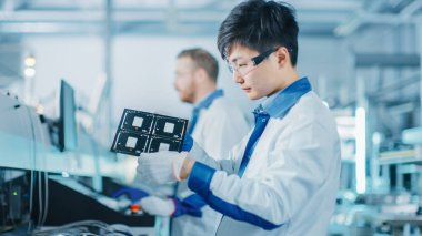 Yüksek Teknoloji Fabrikası: Kalite Kontrol Mühendisi Elektronik Yazıcı Devre Panosunu Hasar için Kontrol Etti. Yüzey Mount Pick ve Place Technology ile PCB için Arkaplan Assembly Line 'da.