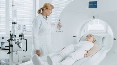 Tıbbi Laboratuvar Radyologları MRI, CT ya da PET taramasında kadın hasta işlemleri yapılıyor. Yüksek Teknolojik Modern Tıbbi Ekipman. Hasta ile Dostane Doktor Sohbetleri.