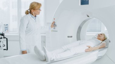 Tıbbi Laboratuvar Radyologları MRI, CT ya da PET taramasında kadın hasta işlemleri yapılıyor. Yüksek Teknolojik Modern Tıbbi Ekipman. Hasta ile Dostane Doktor Sohbetleri.
