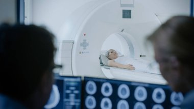 Kontrol Odası 'nda Doktor ve Radyoloji Uzmanı, İşlem ve Beyin Taraması Sonuçlarını İzlerken Tanıyı Tartışıyor, Arka plandaki Hasta MRI veya CT Tarama İşleminden Geçiyor.