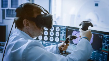Geleceğin kavramı: Sanal Gerçeklik Kulaklığı takan Tıp Laboratuvarı Cerrahı Uzaktan Kontrolcüleri kullanarak Hastayı Tıbbi Robotla Uzaktan Ameliyat Ediyor. Tıpta Yüksek Teknolojik Gelişmeler.