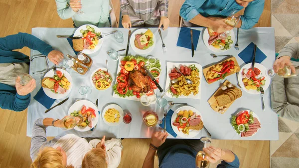 家庭での家族や友人のお祝い、多様な人々のグループがテーブルに集まりました。食べること、飲むこと、楽しい会話をすること。昼間の祭り。トップダウンショット. — ストック写真