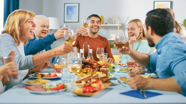 Großes Familien- und Freundesfest zu Hause, vielfältige Gruppe von Kindern, jungen Erwachsenen und alten Menschen, die sich am Tisch versammelt haben, haben Spaß beim Gespräch. Gläser klirren und Toast machen. — Stockfoto