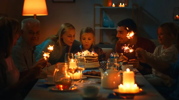 Verjaardagsviering van schattig klein meisje aan de eettafel, meisje met moeder blaast kaarsen uit. Aan tafel verzamelden gelukkige familieleden en vrienden zich om te vieren. — Stockfoto