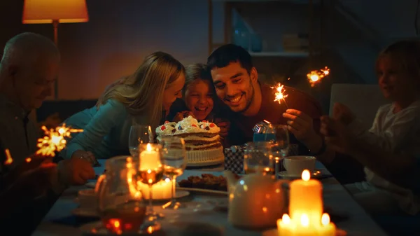 Verjaardagsviering van schattig klein meisje aan de eettafel, omringd door familie en vrienden. Dochter, moeder en vader knuffelen. Gelukkige verjaardag viering. — Stockfoto