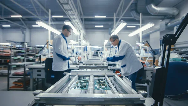 Disparo de una fábrica de electrónica Los trabajadores ensamblan placas de circuitos a mano mientras se encuentra en la línea de montaje. Instalación de fábrica de alta tecnología. — Foto de Stock