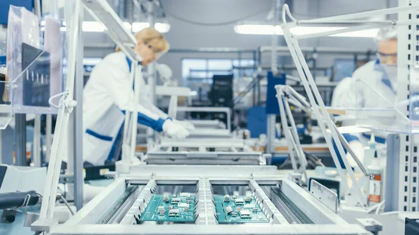 Disparo de una fábrica de electrónica Los trabajadores ensamblan placas de circuitos a mano mientras se encuentra en la línea de montaje. Instalación de fábrica de alta tecnología. — Foto de Stock