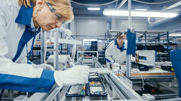 Tiro de uma fábrica de eletrônicos Trabalhadores montar placas de circuito à mão Enquanto ele está na linha de montagem. High Tech Factory Facility. — Fotografia de Stock