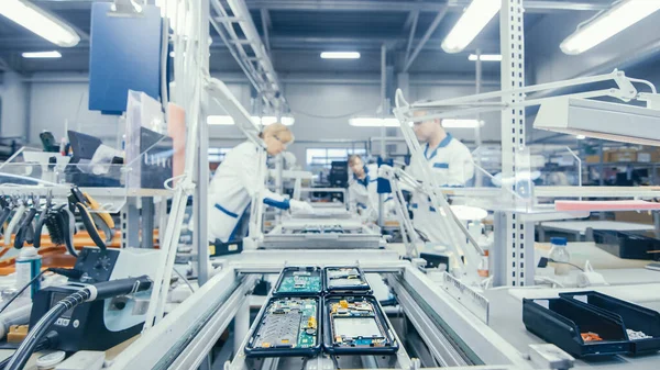 Natáčení elektroniky Tovární dělníci montáž obvodových desek ručně, zatímco to stojí na montážní lince. Zařízení High Tech Factory. — Stock fotografie