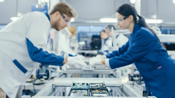 Natáčení elektroniky Tovární dělníci montáž obvodových desek ručně, zatímco to stojí na montážní lince. Zařízení High Tech Factory. — Stock fotografie