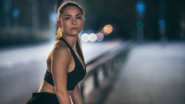 Portrait Prise de vue d'une belle fille de remise en forme confiante en haut sportif noir sur une rue. C'est une brune aux yeux bruns avec ses cheveux attachés dans une queue de cheval. Prise de vue dans un environnement urbain. — Photo