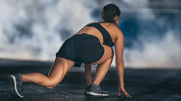 Backshot of a Strong Fitness Girl in Black Athletic Top and Shorts Jogging at Morning on a Foggy Street (en inglés). Atleta se está estirando en un entorno urbano. — Foto de Stock