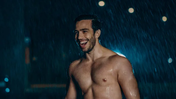 Без сорочки Спортивний м'язистий молодий чоловік тренується в дощову ніч. Він посміхається через успіх у міському середовищі під мостом з автомобілями на задньому плані . — стокове фото