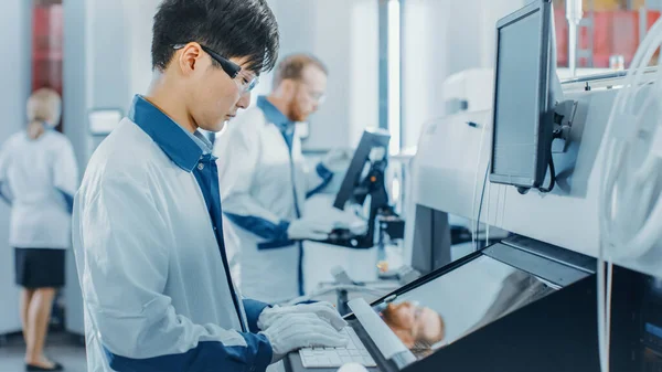 在高科技工厂，亚洲工程师使用计算机编程，为印刷线路板装配线选择和放置电子机械。使用SM机械生产多氯联苯. — 图库照片