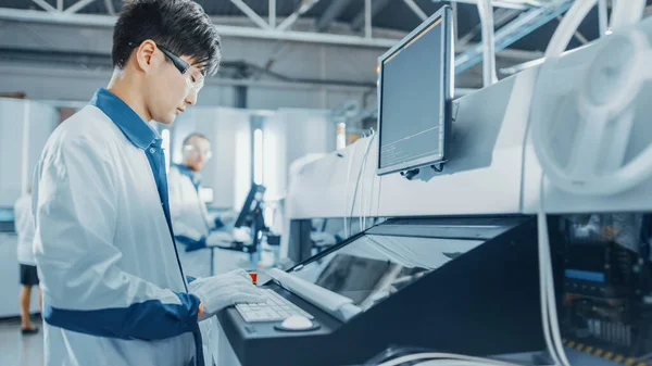 On High Tech Factory Asian Engineer uses Computer for Programming Pick and Place Electronic Machinery for Printed Circuit Board Assembly Line. Výroba plošných spojů se strojním zařízením SM. — Stock fotografie