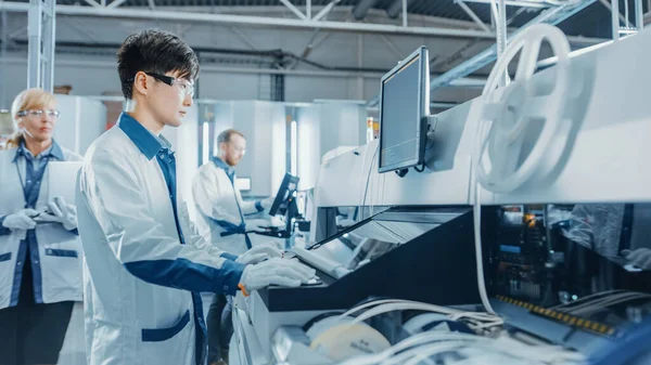 En la fábrica de alta tecnología, el ingeniero asiático utiliza la computadora para programar la línea de ensamblaje Pick and Place Electronic Machinery for Printed Circuit Board. Producción de PCB con SM Machinery. — Foto de Stock