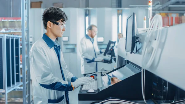 On High Tech Factory Asian Engineer uses Computer for Programing Pick and Place Electronic Machinery for Printed Circuit Board Assembly Line. Výroba plošných spojů se strojním zařízením SM. — Stock fotografie