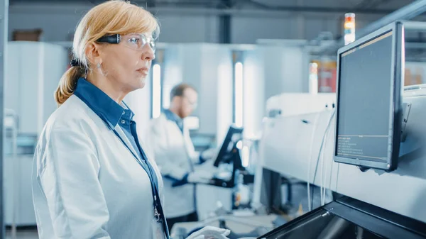 Retrato Tiro de uma engenheira feminina em alta tecnologia Fábrica usa computador para programar Pick and Place Máquinas eletrônicas para placa de circuito impresso Superfície Mount Assembly Line. Produção de PCB com — Fotografia de Stock