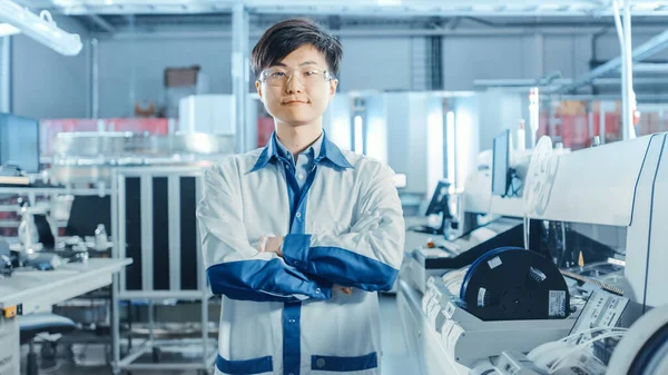 On High-Tech Factory: Portrait of Asian Worker with Crossed Arms (англійською). На задньому плані електронна друкована платформа Асамблея асамблеї лінії, яка використовує технології поверхневої гори і побутові прилади. — стокове фото