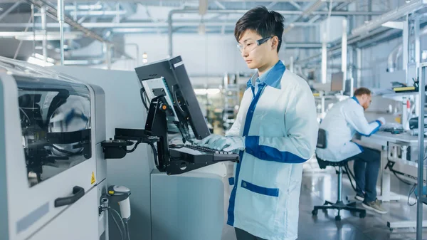 On High Tech Factory Asian Engineer Uses Computer for Programing Pick and Place Electronic Machinery for Printed Circuit Board Surface Mount Assembly Line Виробництво PCB з SMT Machinery. — стокове фото