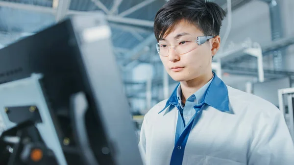 Portræt Shot af asiatisk ingeniør på High Tech Factory Bruger Computer til programmering Pick and Place Elektronisk Maskiner til trykt kredsløbstavle Surface Mount Assembly Line. Produktion af PCB med SMT - Stock-foto