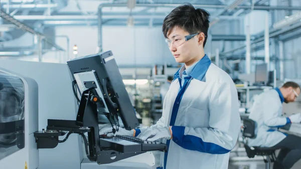 On High Tech Factory Asian Engineer Uses Computer for Programing Pick and Place Electronic Machinery for Printed Circuit Board Surface Mount Assembly Line Виробництво PCB з SMT Machinery. — стокове фото