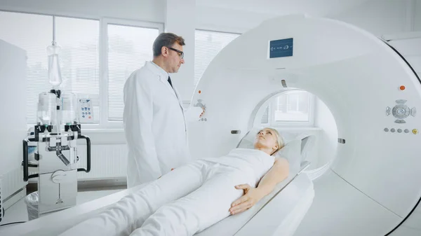 In Medical Laboratory Radiologist Controls MRI or CT or PET Scan with Female Patient Undergoing Procedure. Professional Doctor Conducts Emergency Checkup Procedure with Advanced Medical Technologies.