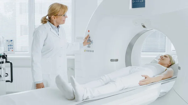 En el laboratorio médico el radiólogo controla la resonancia magnética o la tomografía computarizada o la exploración de la PET con el paciente femenino que se somete a procedimiento. Equipos médicos modernos de alta tecnología. Amistoso Doctor Chats con Paciente. — Foto de Stock