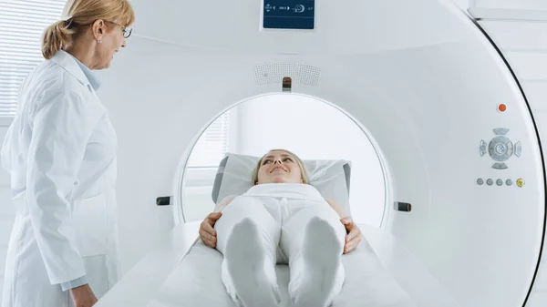 In the Medical Laboratory Female Patient Lying on a CT or MRI Scan Bed Undergoes Scanning Procedure Under Supervision of Professional Radiologist.