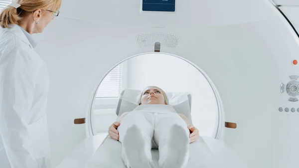 Detailní záběr Portrét pacientky ležící na CT nebo MRI skenu, postel se pohybuje uvnitř stroje, zatímco to skenuje její tělo a mozek. V lékařské laboratoři s high-tech zařízení. — Stock fotografie