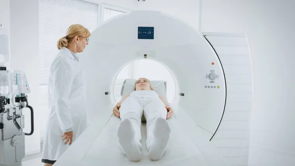 En el laboratorio médico, la radióloga femenina controla la resonancia magnética o la tomografía computarizada con una paciente sometida a un procedimiento. Equipos médicos modernos de alta tecnología. — Foto de Stock