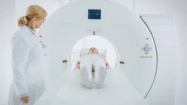 En el laboratorio médico, la radióloga femenina controla la resonancia magnética o la tomografía computarizada o la tomografía computarizada (PET) con pacientes sometidas a procedimiento. El médico realiza análisis de emergencia con tecnologías médicas avanzadas. — Foto de Stock