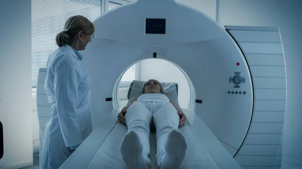 In Medical Laboratory Female Radiologist Controls MRI or CT or PET Scan with Female Patient Undergoing Procedure. Doctor Conducts Emergency Scanning with Advanced Medical Technologies. In Blue Tone. — Stock Photo, Image