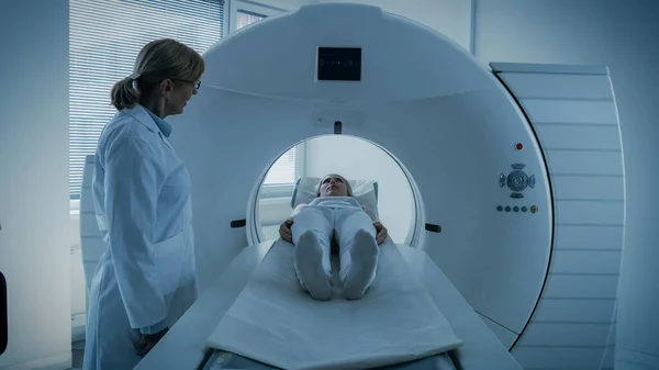 En el laboratorio médico, la radióloga femenina controla la resonancia magnética o la tomografía computarizada o la tomografía computarizada (PET) con pacientes sometidas a procedimiento. El médico realiza análisis de emergencia con tecnologías médicas avanzadas. En tono azul. —  Fotos de Stock