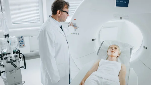 En el laboratorio médico el radiólogo masculino controla la resonancia magnética o la tomografía computarizada o la exploración de la PET con el paciente femenino que se somete a procedimiento. Equipos médicos modernos de alta tecnología. —  Fotos de Stock